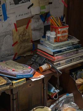 A colorful workspace with manga sketches and comic books spread out on a wooden desk.