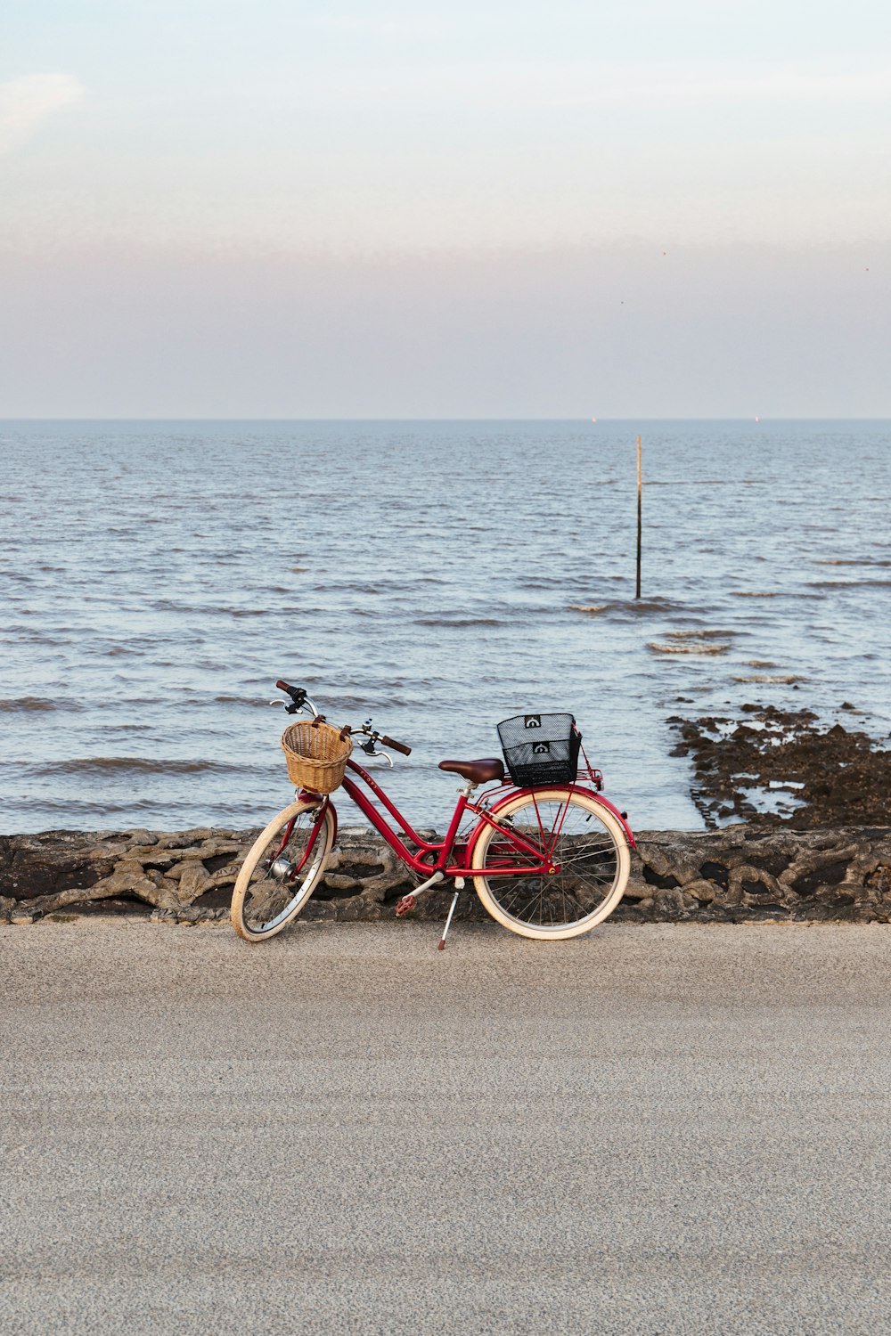 a red bike parked on the side of a road next to the ocean