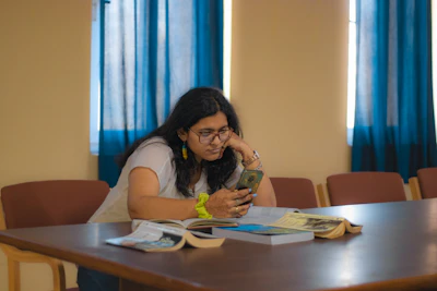 a woman sitting at a table looking at her cell phone