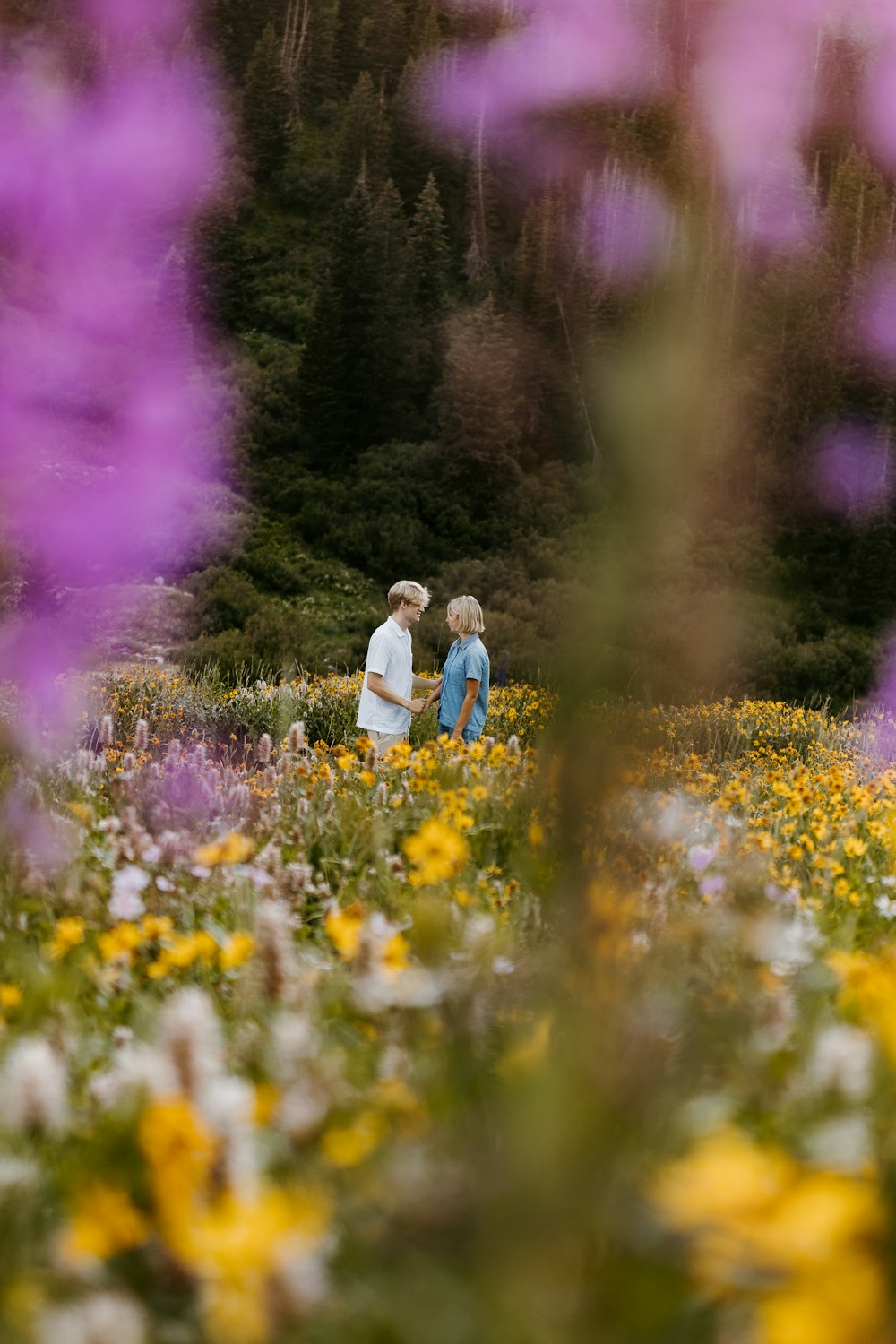 a couple of people standing in a field of flowers