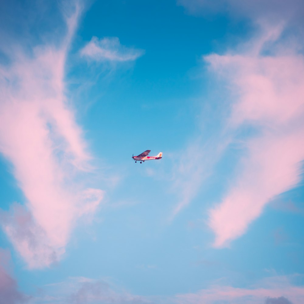 an airplane flying in the sky with a pink cloud
