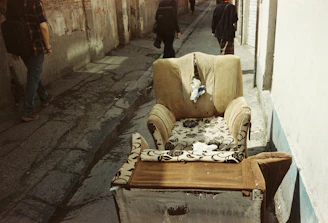 A mover gently carrying a vintage armchair down a staircase in a residential building.