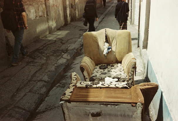 A mover gently carrying a vintage armchair down a staircase in a residential building.