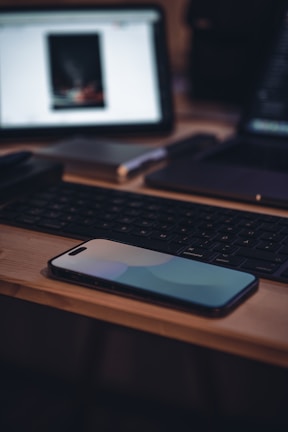 Close-up of a sleek smartphone on a wooden desk with a soft blue background.