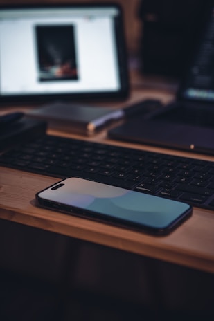 Close-up of a modern smartphone on a wooden desk.
