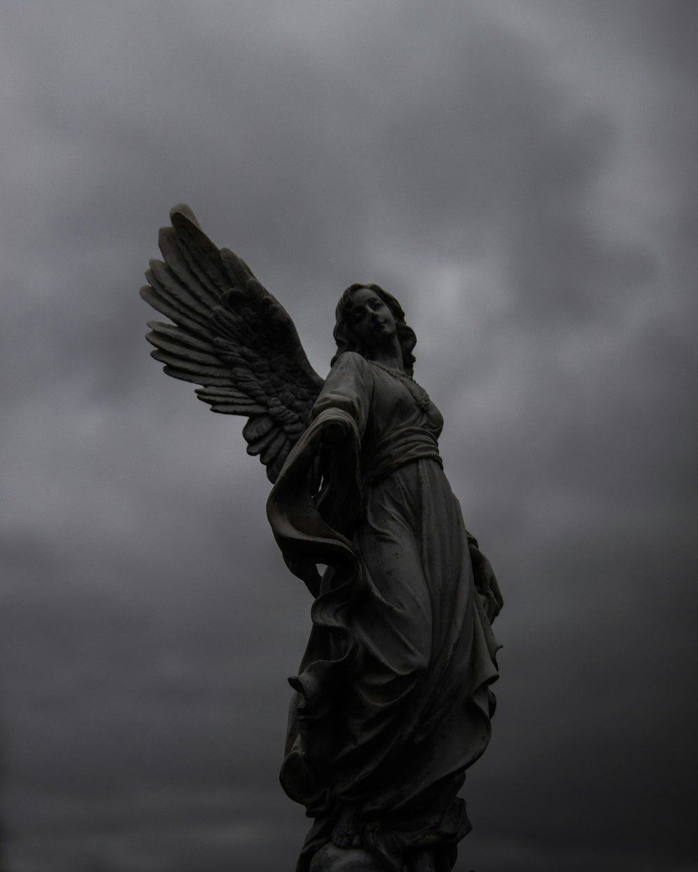 a statue of an angel on a cloudy day