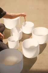 a man sitting on the ground next to white bowls
