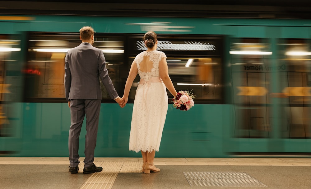 a bride and groom hold hands as a train passes by