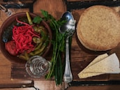 A rustic wooden table displaying jars of zok pickles alongside fresh produce scraps.