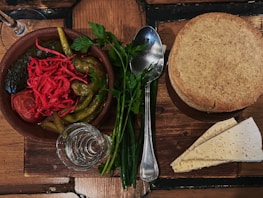 A rustic wooden table displaying jars of zok pickles alongside fresh produce scraps.