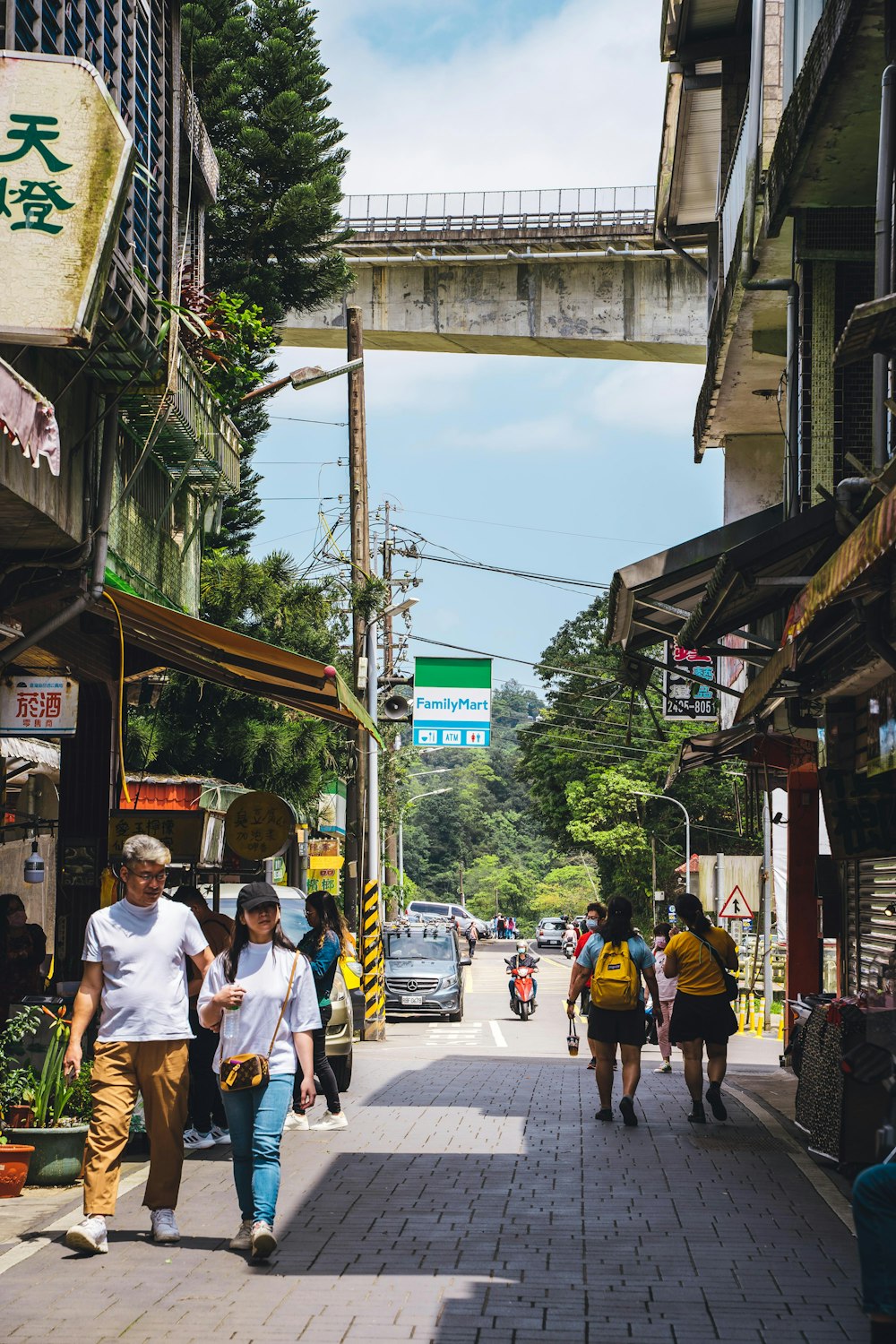 a group of people walking down a street next to tall buildings