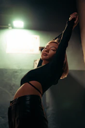 A dynamic shot of a woman stretching in a modern, urban setting wearing streamlined leggings and a fitted top.