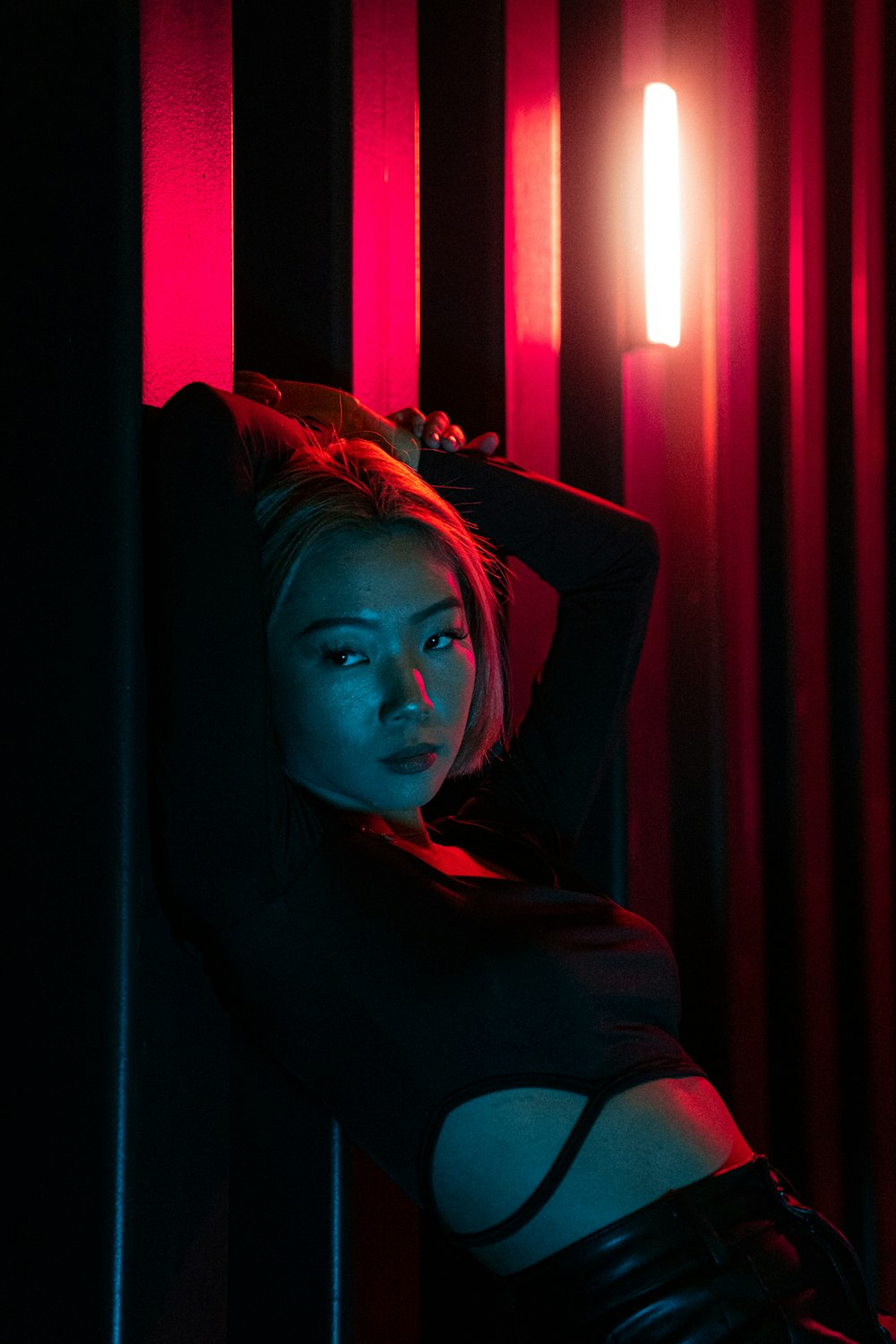 a woman leaning against a wall in a dark room