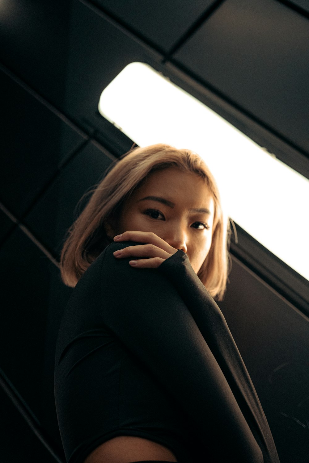 a woman standing in front of a window with her hand on her face