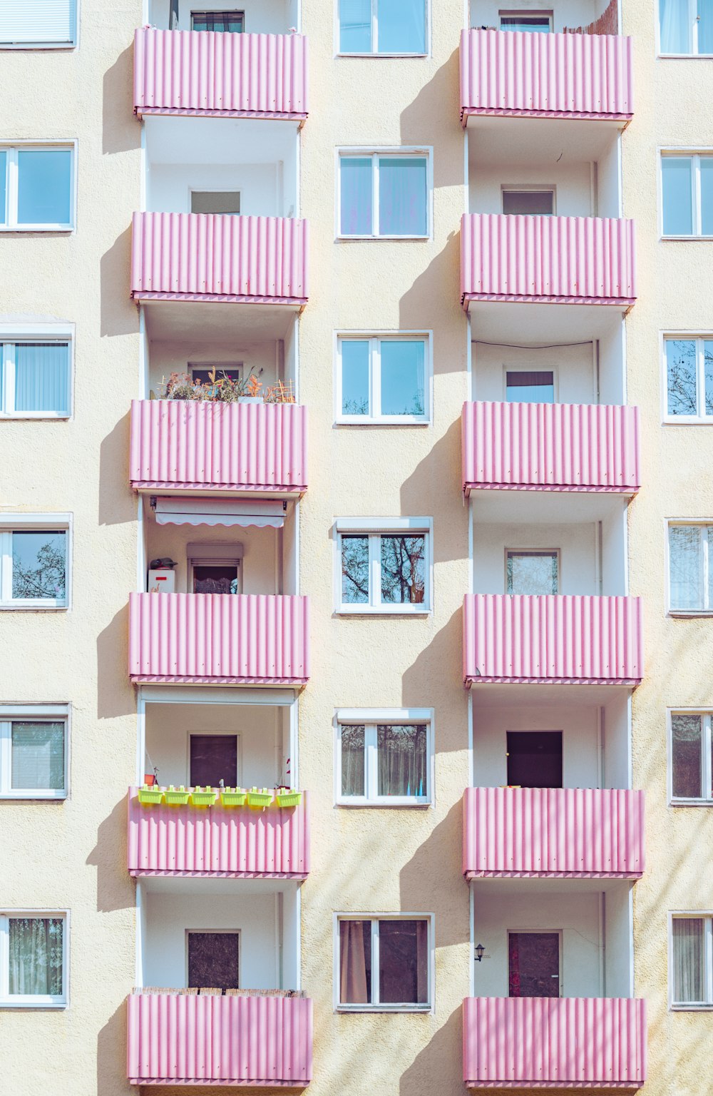 Ein rosa-weißes Gebäude mit Balkonen und Fenstern