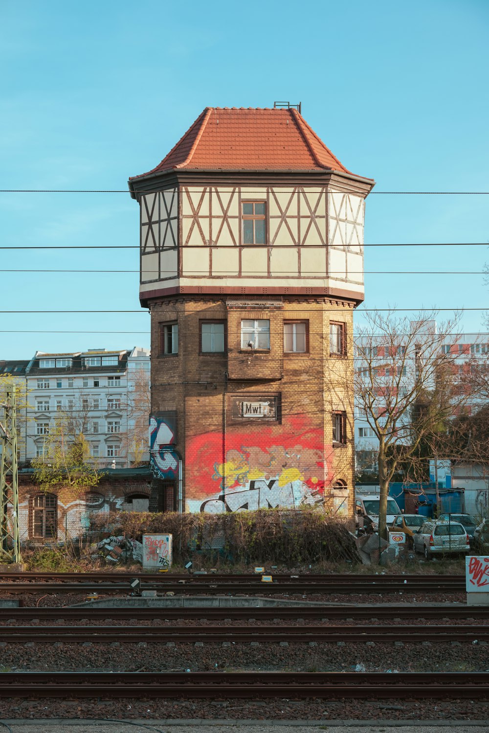 a tall building with a red roof next to a train track