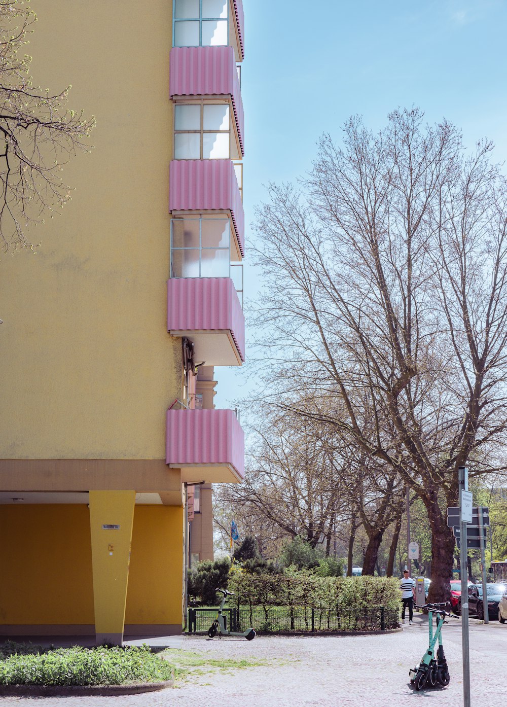 a pink and yellow building next to a tree