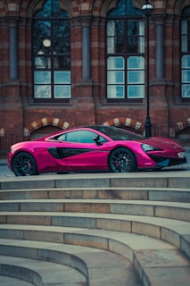 A sleek pink car parked in a modern urban setting.