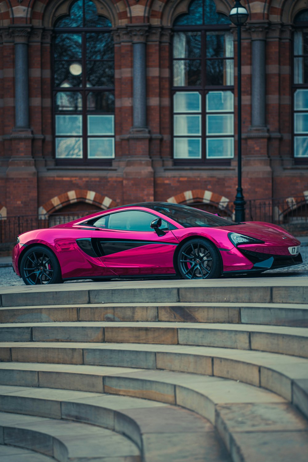 a pink sports car parked in front of a building