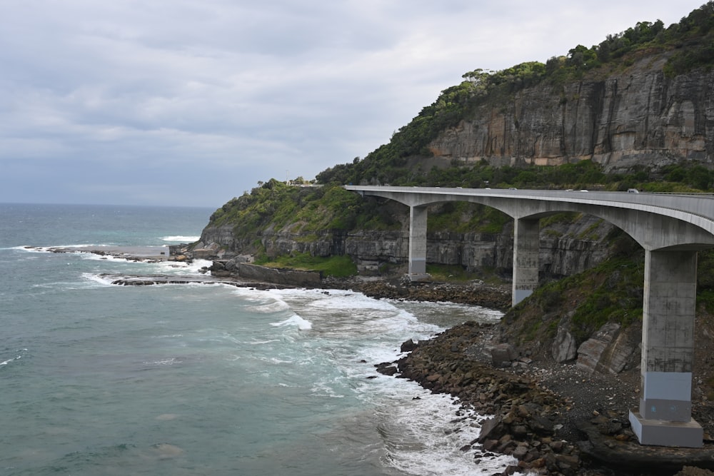 a bridge over a body of water next to a cliff