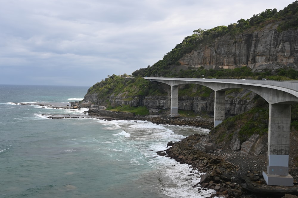 un pont au-dessus d’un plan d’eau à côté d’une falaise