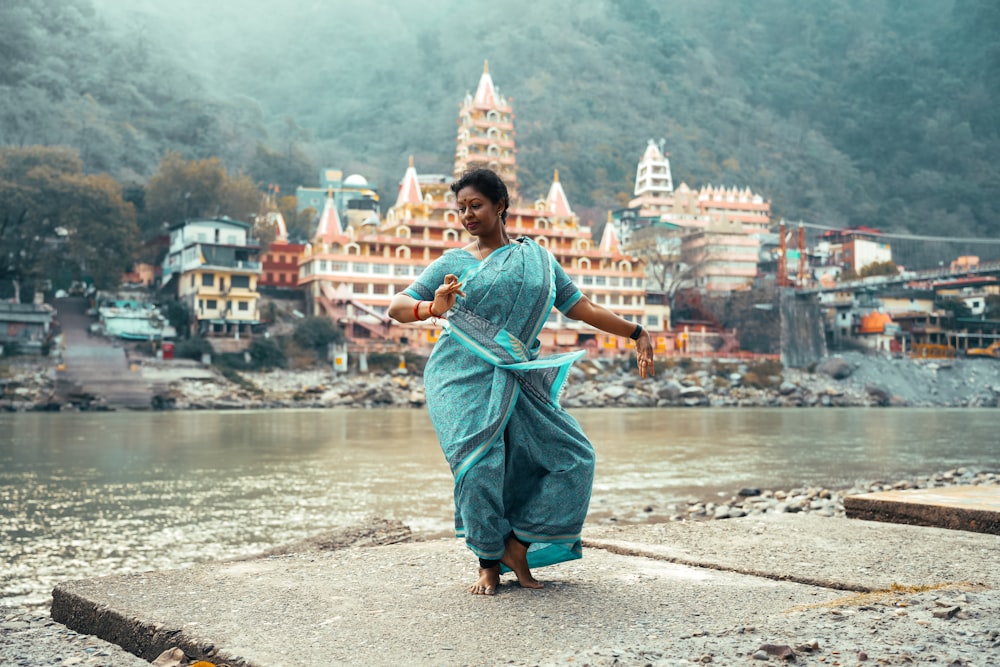 a woman in a blue sari dancing by a river