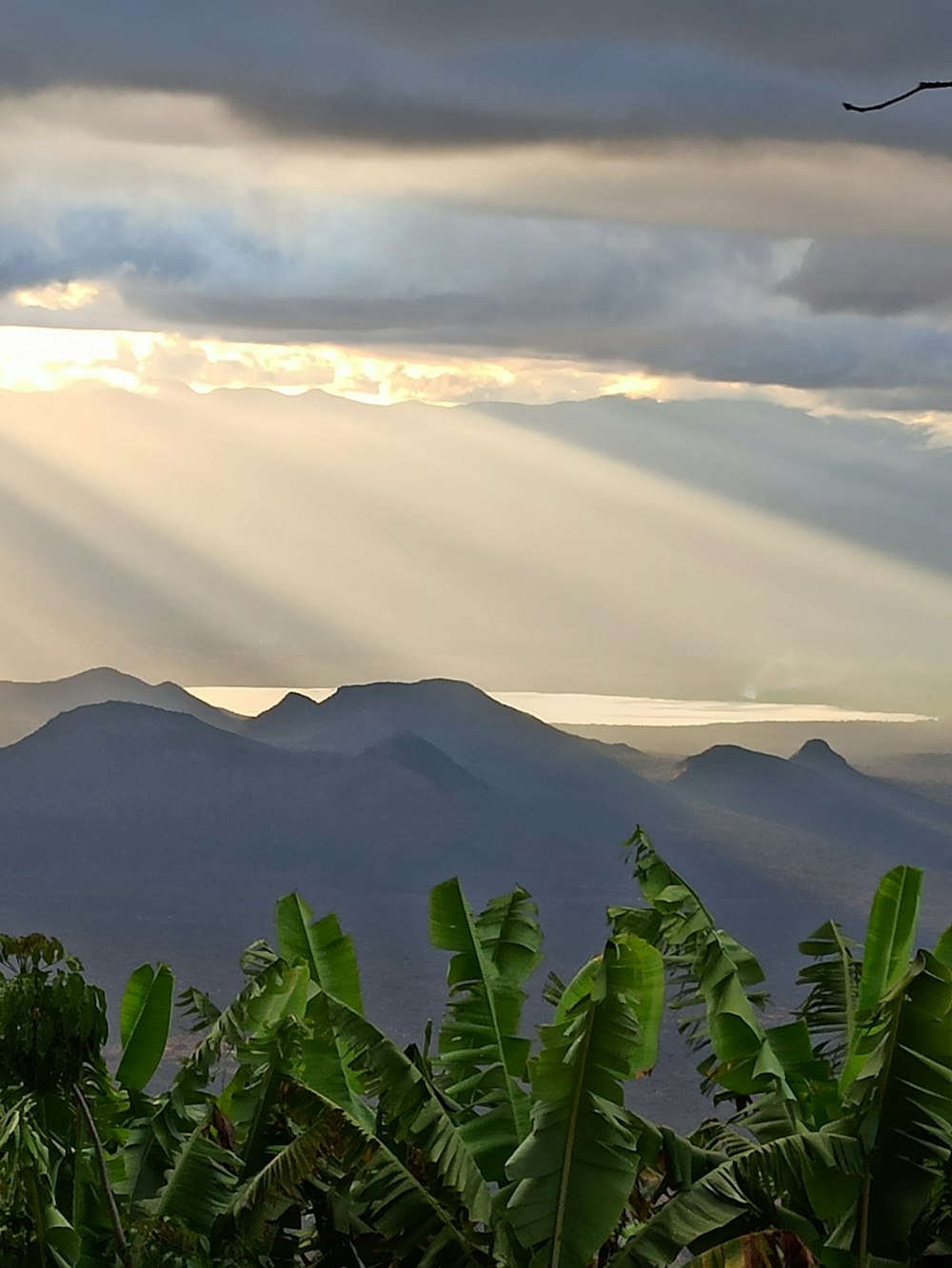 the sun is shining through the clouds over the mountains