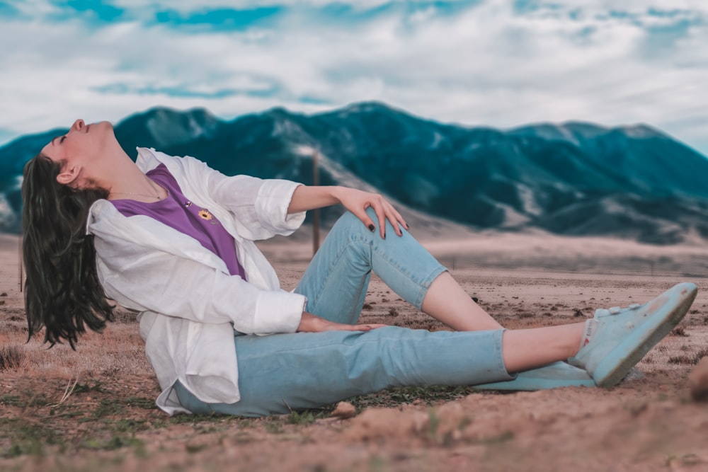 a woman sitting on the ground in the desert