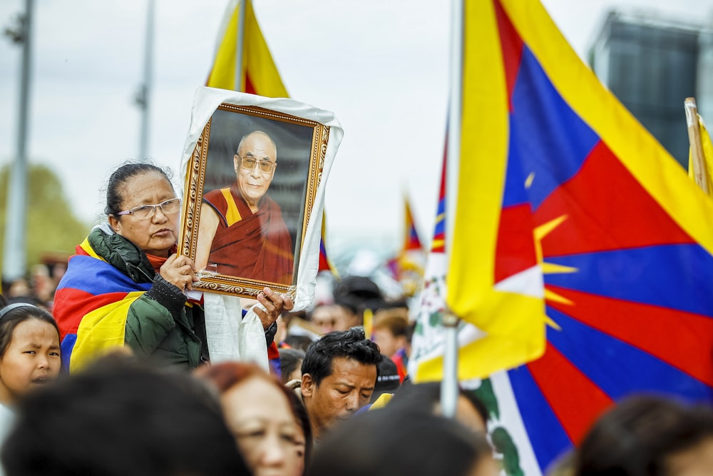 a person holding a picture of a man in a crowd of people