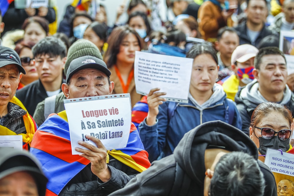 a crowd of people holding signs and wearing face masks