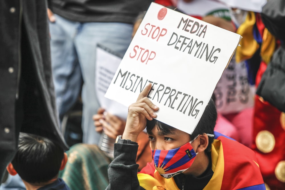 a young boy holding a sign that says stop defamiting