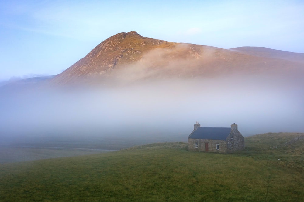 a house in the middle of a field with a mountain in the background