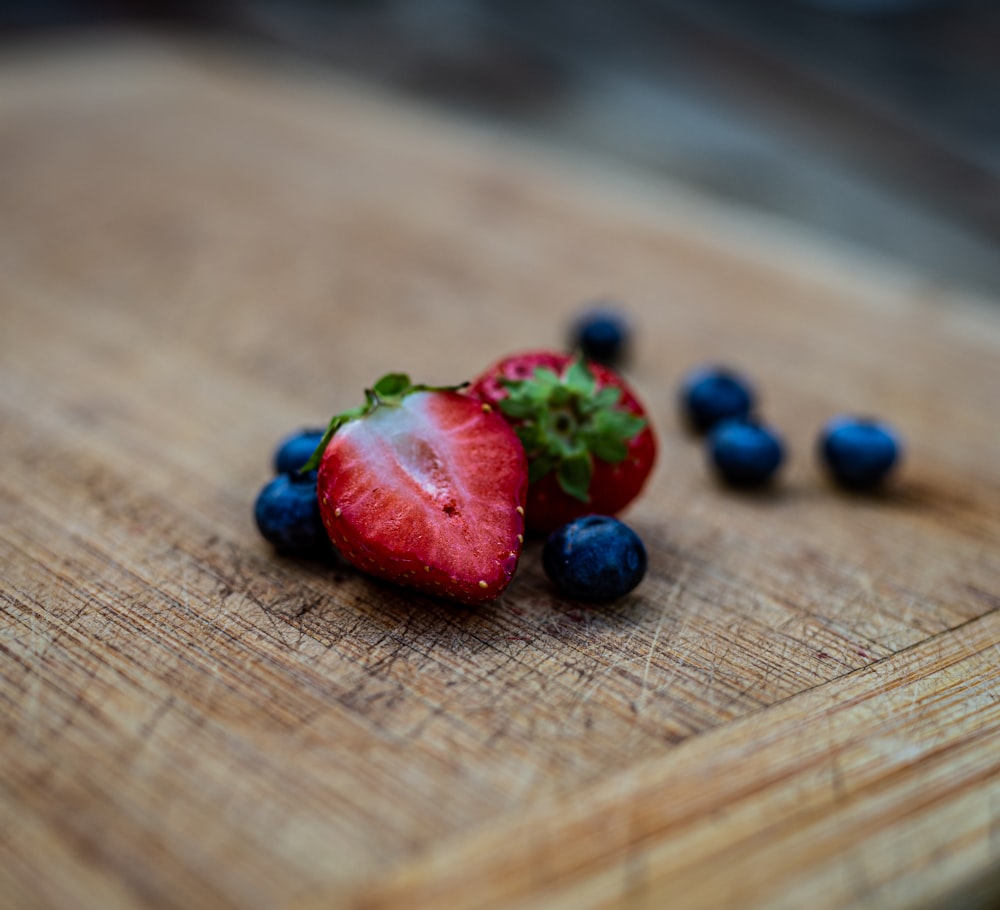 two strawberries and blueberries on a cutting board