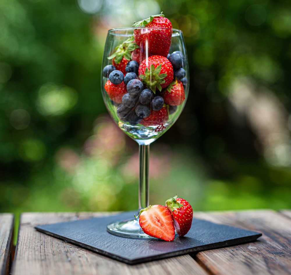 a glass of water with strawberries and blueberries in it