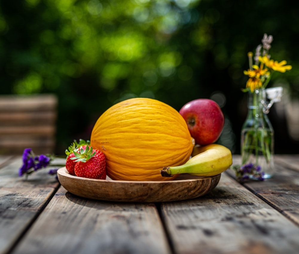 a bowl of fruit sitting on top of a wooden table