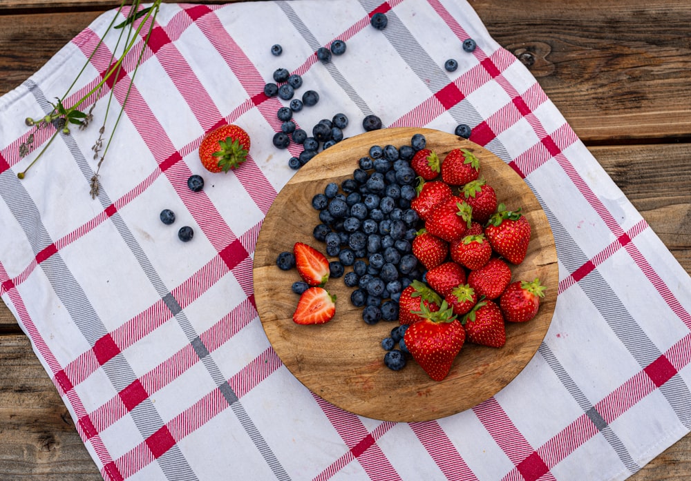 a wooden plate topped with berries and blueberries