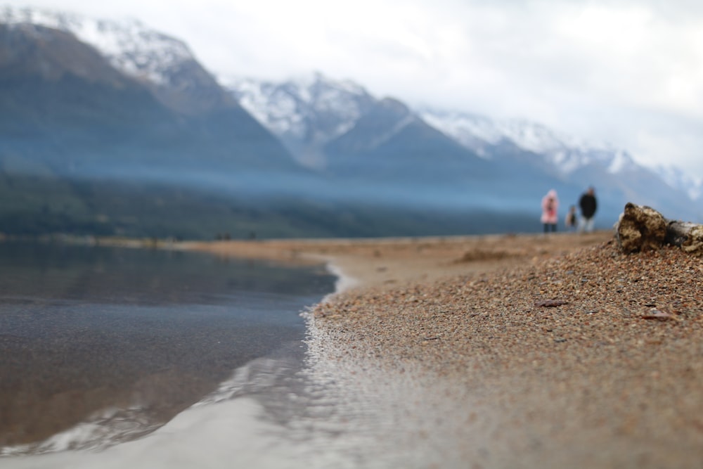 a couple of people standing on top of a sandy beach