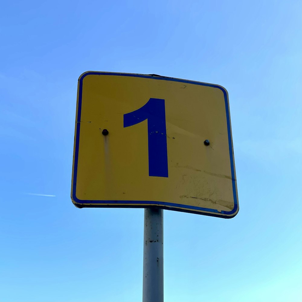 a blue and yellow street sign with the number one on it