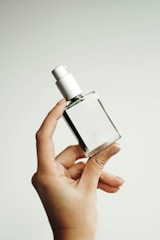 a woman's hand holding a bottle of perfume