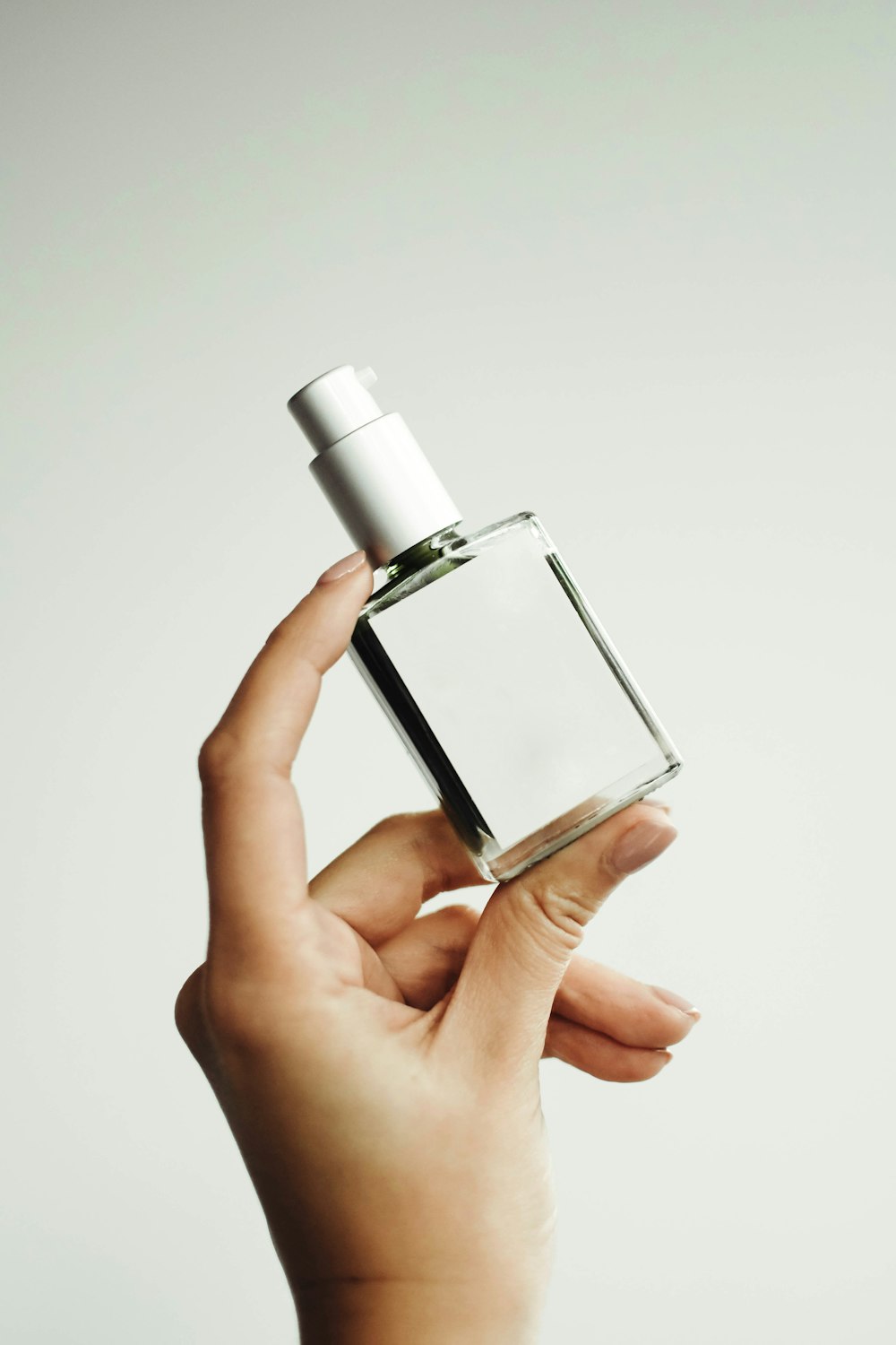 a woman's hand holding a bottle of perfume