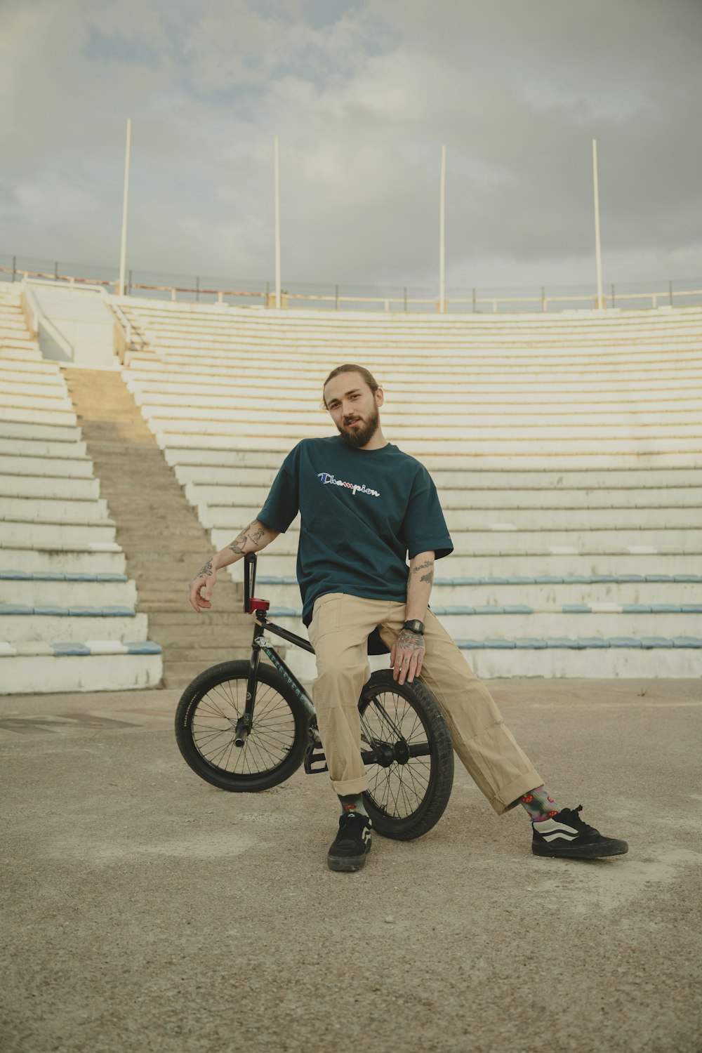 a man sitting on a bike in front of a stadium
