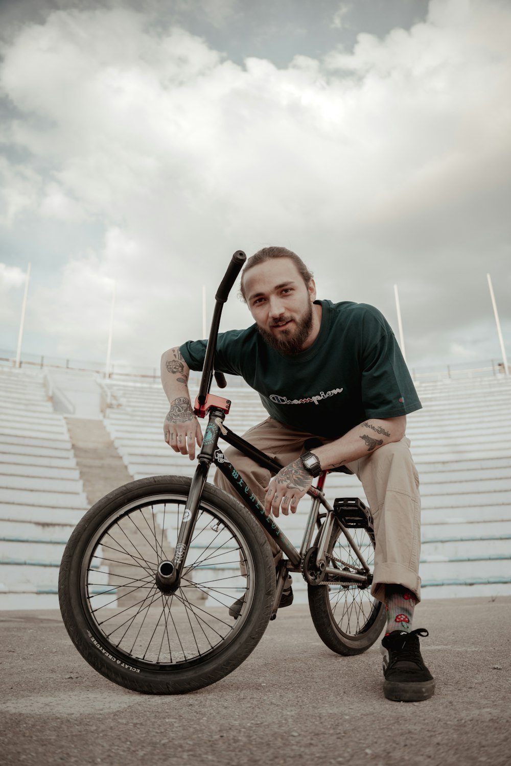 a man sitting on top of a bike in front of a stadium