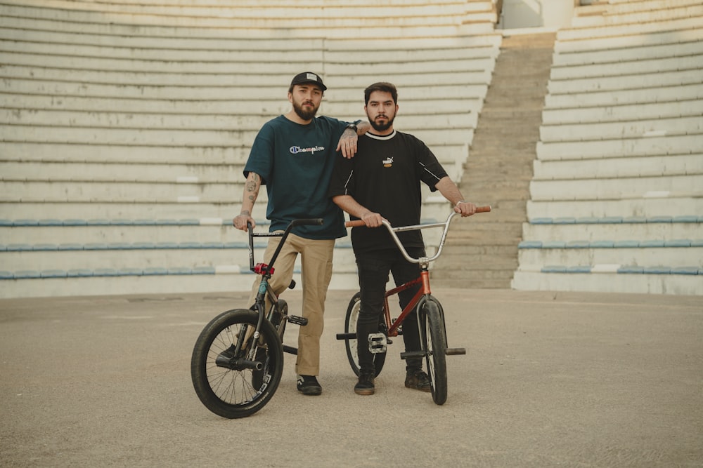 a couple of men standing next to a bike