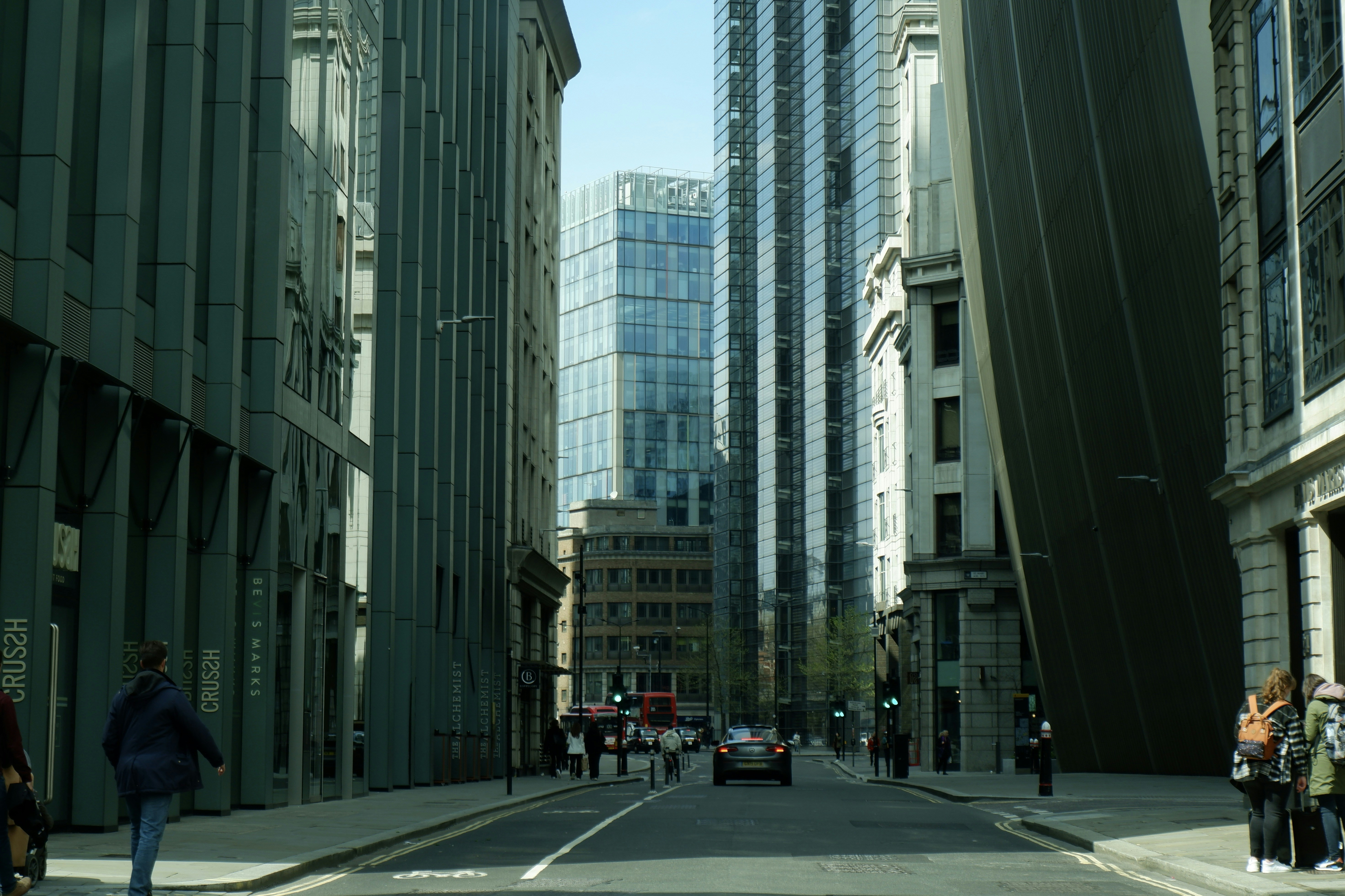 a group of people walking down a street next to tall buildings