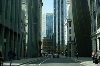 a group of people walking down a street next to tall buildings