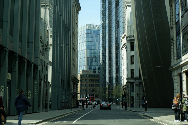a group of people walking down a street next to tall buildings