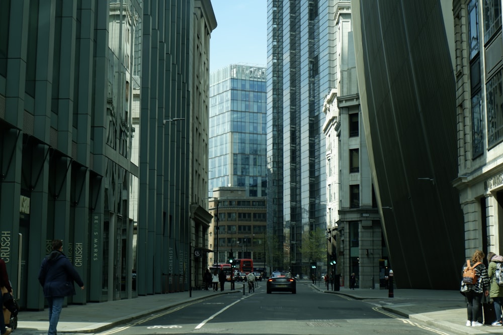 a group of people walking down a street next to tall buildings