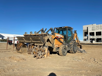 A vibrant heavy machinery loader in action at a construction site under bright blue skies.
