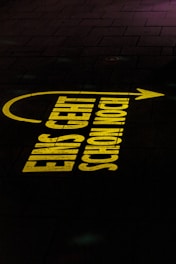 Bright yellow text projected onto a dark pavement reads 'EINS GEHT SCHON NOCH!' with an arrow pointing to the right.