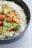 A bowl of steaming white rice served with fresh vegetables.